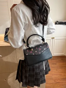 Sac bandoulière floral avec motifs cerise et nœud porté par le mannequin