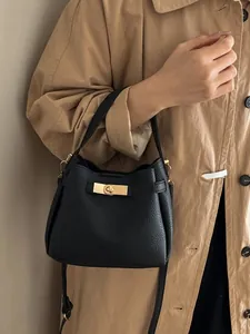 Elegant black lychee grain leather bucket bag with gold clasp shown on model