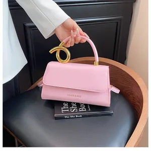 Pink leather shoulder bag detail with unique golden knotted metal handle and lettering