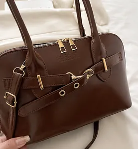 Detail der glänzenden braunen Muscheltasche mit Doppelreißverschluss und Golddekor