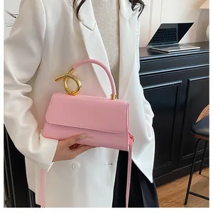 Pink PU leather handbag with unique gold metal handle shown on a model in a white blazer