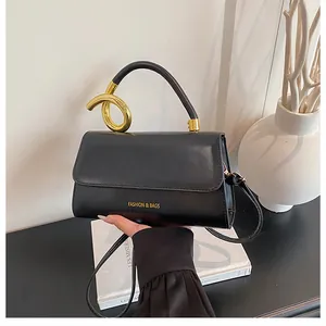 Detail of black leather handbag featuring a unique gold twisted metal handle and logo