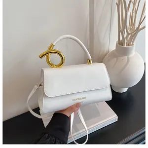 Detail of white leather handbag featuring gold ring handle and FASHION & BAGS text logo