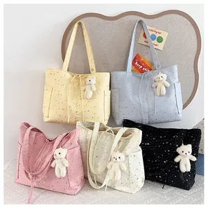 Detalle de bolsos tote de nailon de colores con patrones de estrellas y colgantes de oso