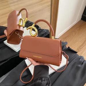 Brown rectangular faux leather shoulder bag with gold twist buckle and mirror reflection