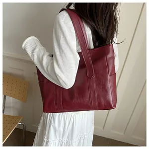 Detail des breiten Schultergurts und der weinroten PU-Ledertextur einer Shopper-Tasche