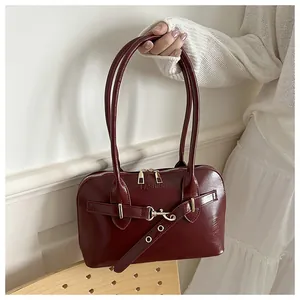 Detail der weinroten glänzenden Ledertasche mit FASHION-Schriftzug und Metallbeschlägen