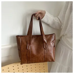 Detail der Vintage braunen PU-Leder Tragetasche mit verstärkten Griffen und Seitentasche