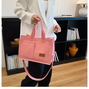 Pink canvas tote bag detail showing dual handles, long shoulder strap and front pockets