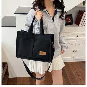 Detailed view of black canvas tote bag with front pockets and adjustable strap for women