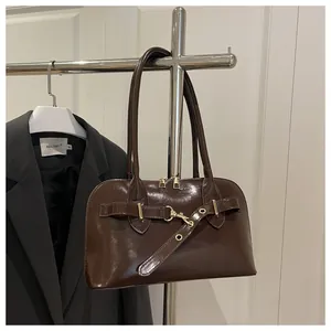 Nahaufnahme einer dunkelbraunen Lackleder-Tasche mit Metallschnalle und Schultergurt