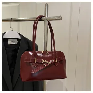 Detail der weinroten Lackleder-Muscheltasche mit Zierschnallen und glänzendem Finish