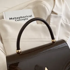 Détail du sac en cuir verni marron brillant avec poignée sphérique en métal doré