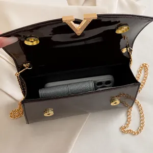 Détail de l'intérieur du sac en cuir verni avec fermoir en V doré et bandoulière chaîne