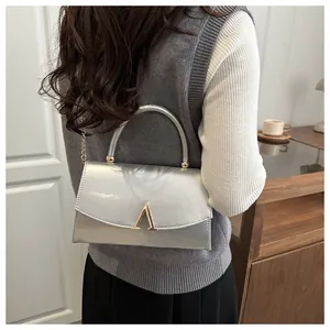 Détail du sac argenté métallisé avec fermoir doré en V et bandoulière chaîne