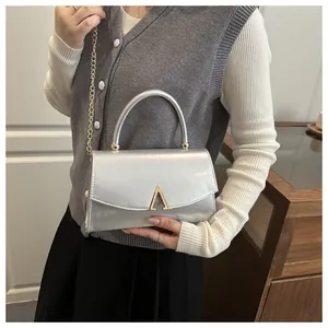Détail du sac argenté avec boucle dorée en forme de A et bandoulière en chaîne métal