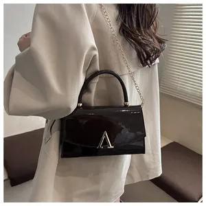 Détail du sac en cuir verni bordeaux avec boucle en V dorée et fine bandoulière chaîne