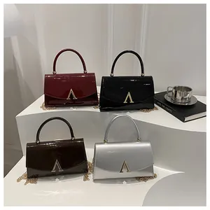 Gros plan de quatre sacs en cuir brillant bordeaux, noir, café et argent avec chaîne