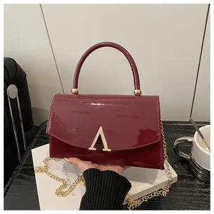 Gros plan sur un sac en cuir verni bordeaux avec une boucle dorée en lettre A