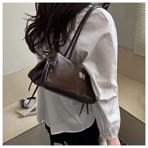 Detail showing high-quality dark brown leather texture and silver metal nameplate on the bag