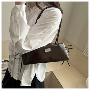 Side view of a vintage dark brown leather shoulder bag on a model in a warm setting