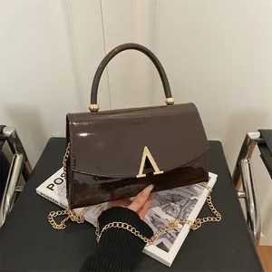 Sac à main en cuir verni marron foncé avec fermoir doré et bandoulière chaîne