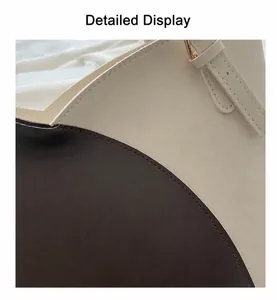 Detail of color-block tote bag showing cream and brown leather texture with gold buckle