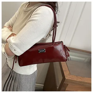 Detail of burgundy glossy leather underarm bag with metal plaque and slim shoulder straps