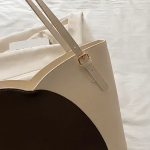 Close-up of contrast color tote bag showing fine stitching and gold buckle details