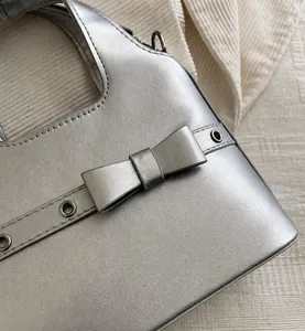 Detailansicht der silbernen Ledertasche mit schicker Schleife und Metallösen-Akzenten