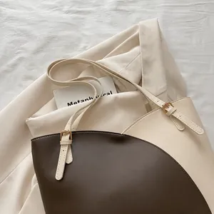 Detail of contrast-color tote bag featuring adjustable leather handle and stitching