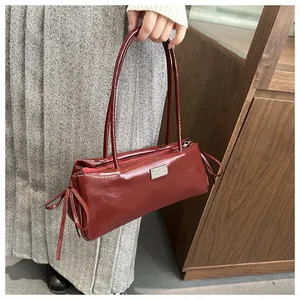Detail of wine red baguette bag with side ribbon bows and silver logo plaque