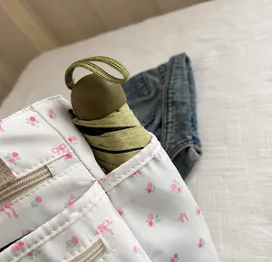 Detailopname van het zijvak van de bloemen canvas tas met een groene opvouwbare paraplu