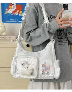 Detail der weißen Ita-Tasche mit Sternmuster, Rüschenriemen und transparentem PVC-Fenster