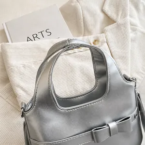 Detailansicht des silbernen PU-Ledergriffs und der schicken Schleife an der Handtasche