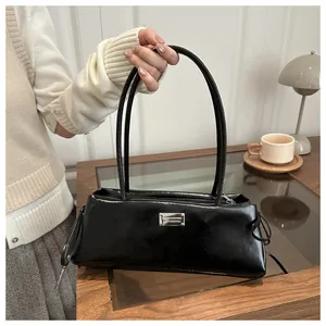 Detailed shot of black patent leather baguette bag with silver logo and thin dual straps