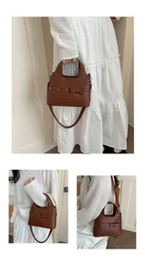 Detail of brown bucket bag with bow decoration and metal eyelets on white dress