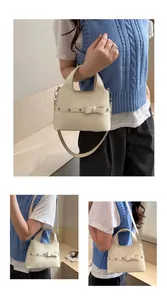 Detail of cream white leather bucket bag featuring a decorative bow and metallic studs