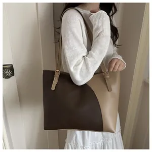 Detail of a large brown contrast tote bag with long straps on a model's shoulder