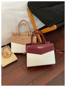 Detail of elegant two-tone handbags with V-shaped embossing and golden metal hardware