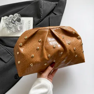 Primer plano del bolso de mano marrón de cocodrilo con remaches dorados y pliegues