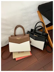 Detailed view of bicolor envelope handbags with V-shaped quilting and metal logo detailing