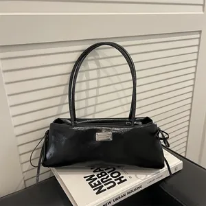 Classic black oil-wax leather baguette shoulder bag with silver plaque on a minimal backdrop