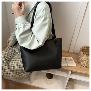 Detail of a black contrast tote bag with curved stitching and side zipper on a model