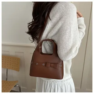 Brown retro bucket bag with bow detail and metallic eyelets shown in lifestyle setting