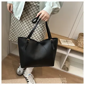 Detail view of black matte tote bag with curved overlapping design and gold buckle strap