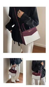 Detail of color-block PU leather handbag showing top handle and adjustable strap