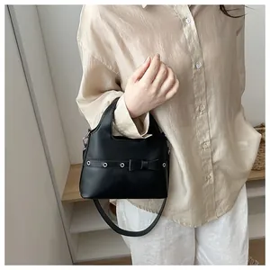 Detail of black faux leather handbag with bow decoration and silver eyelets detail