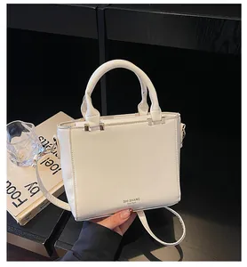 Macro shot of white leather texture and gold hardware on a minimalist square crossbody bag