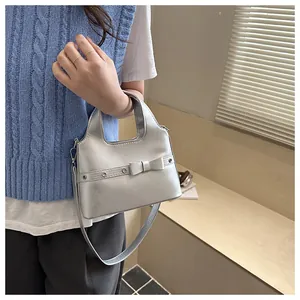 Detail of silver metallic mini handbag with bow decor and dual straps in a lifestyle setting